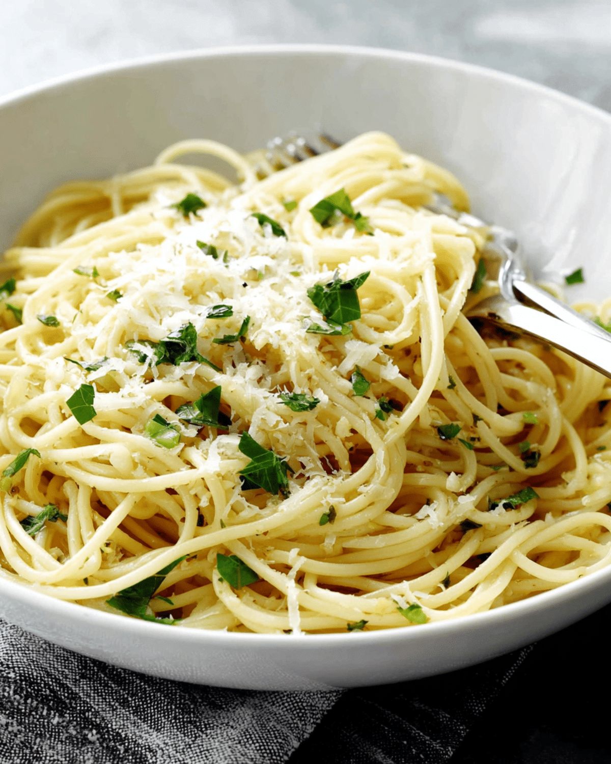 Bowl of easy lemon butter garlic pasta topped with fresh parsley and grated Parmesan cheese.
