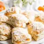 Plate of flaky apricot scones drizzled with white icing.