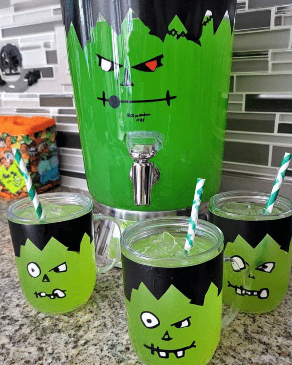 Frankenstein Green Punch served in themed glasses and a large Frankenstein drink dispenser with green liquid and straws.