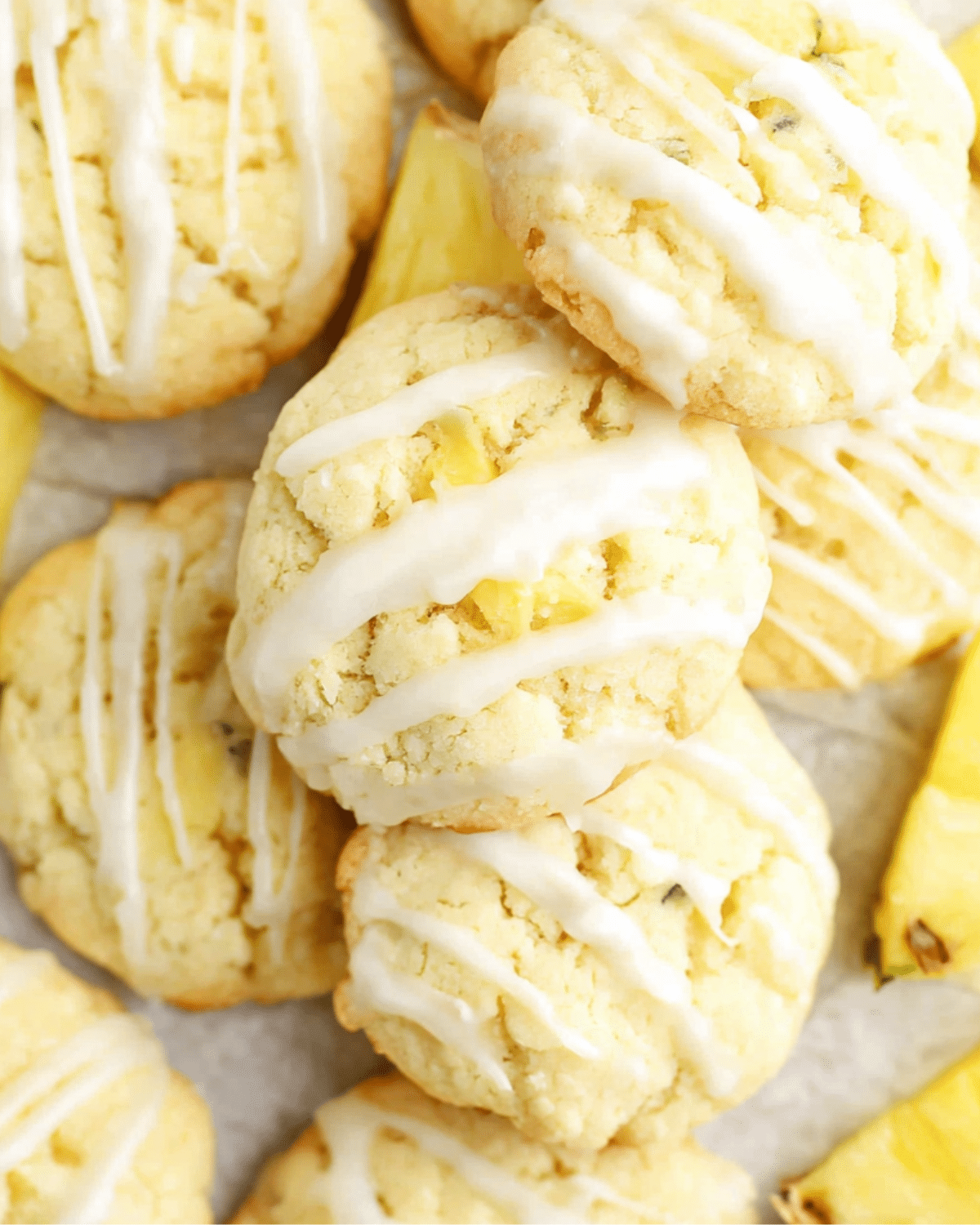 Close-up of Pineapple Cookies drizzled with white glaze, surrounded by fresh pineapple slices.