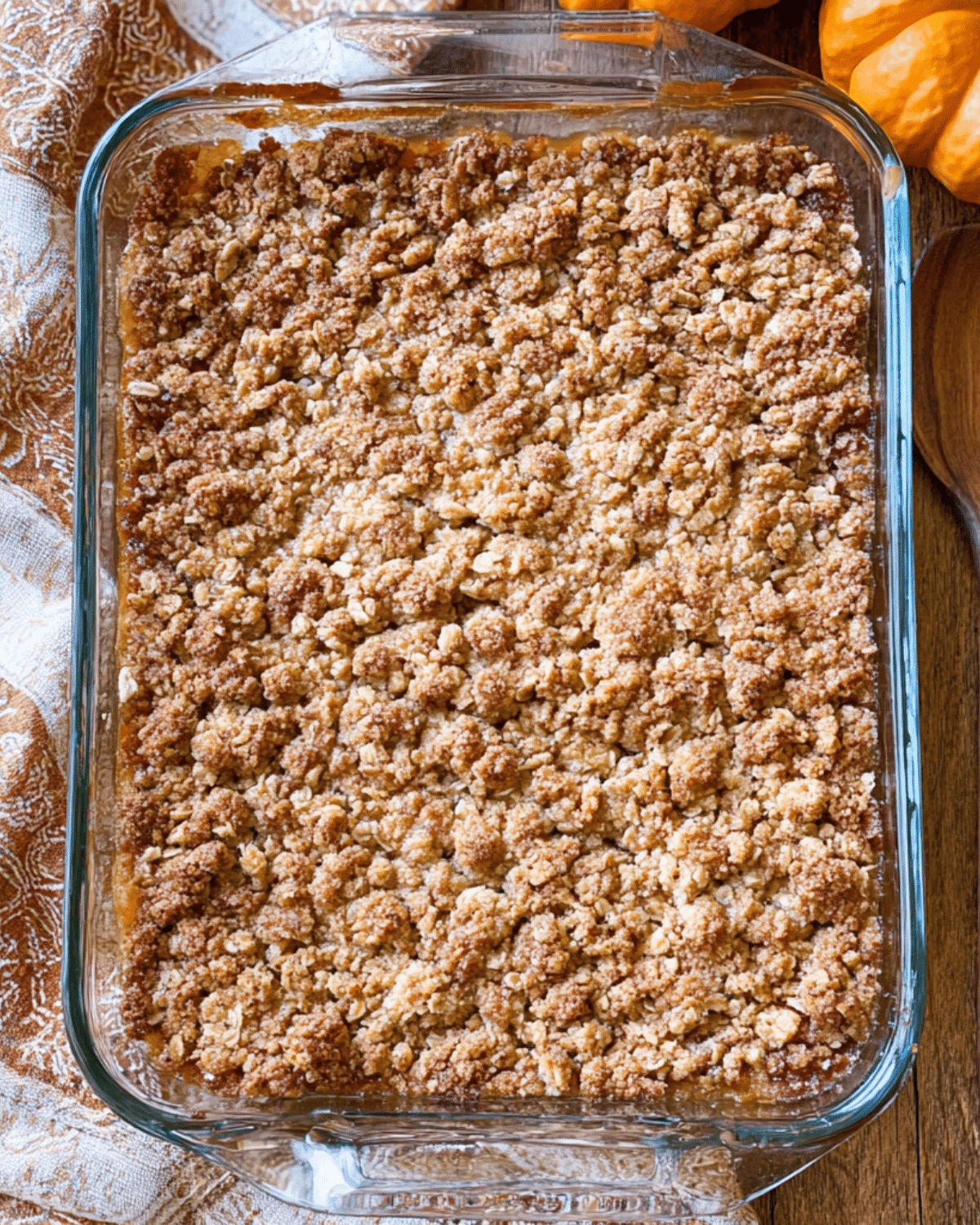 Pumpkin crisp in a glass baking dish with a golden brown oat crumble topping.