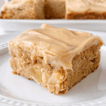 Close-up of apple cinnamon blondies topped with maple cream cheese frosting on a white plate.