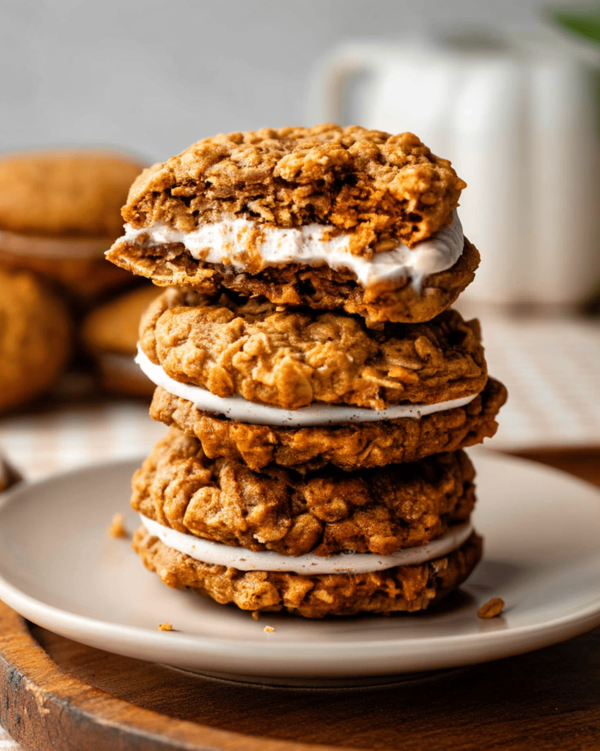 Stack of pumpkin oatmeal cream pies filled with white cream, with the top cookie partially bitten.