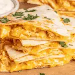 Stack of crispy Air Fryer Buffalo Chicken Quesadillas filled with melted cheese and shredded chicken, garnished with cilantro.