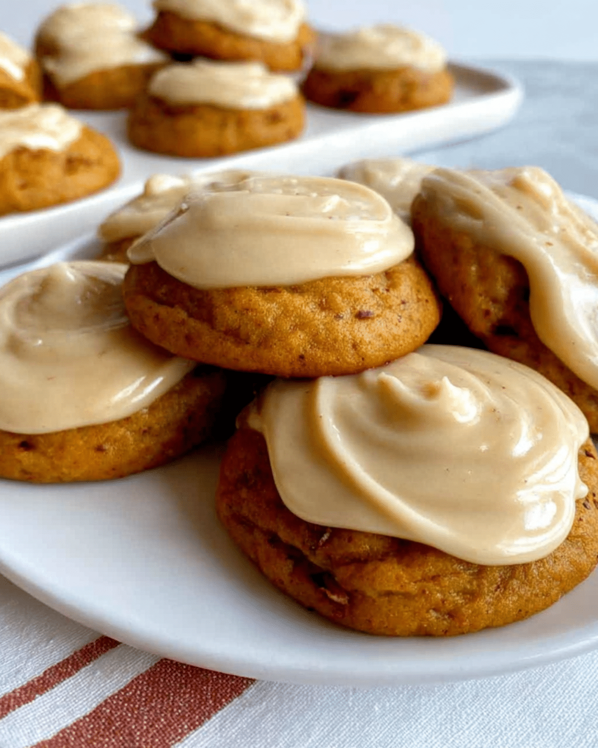 A plate of soft Amish Pumpkin Cookies with Frosting, topped with creamy beige icing.