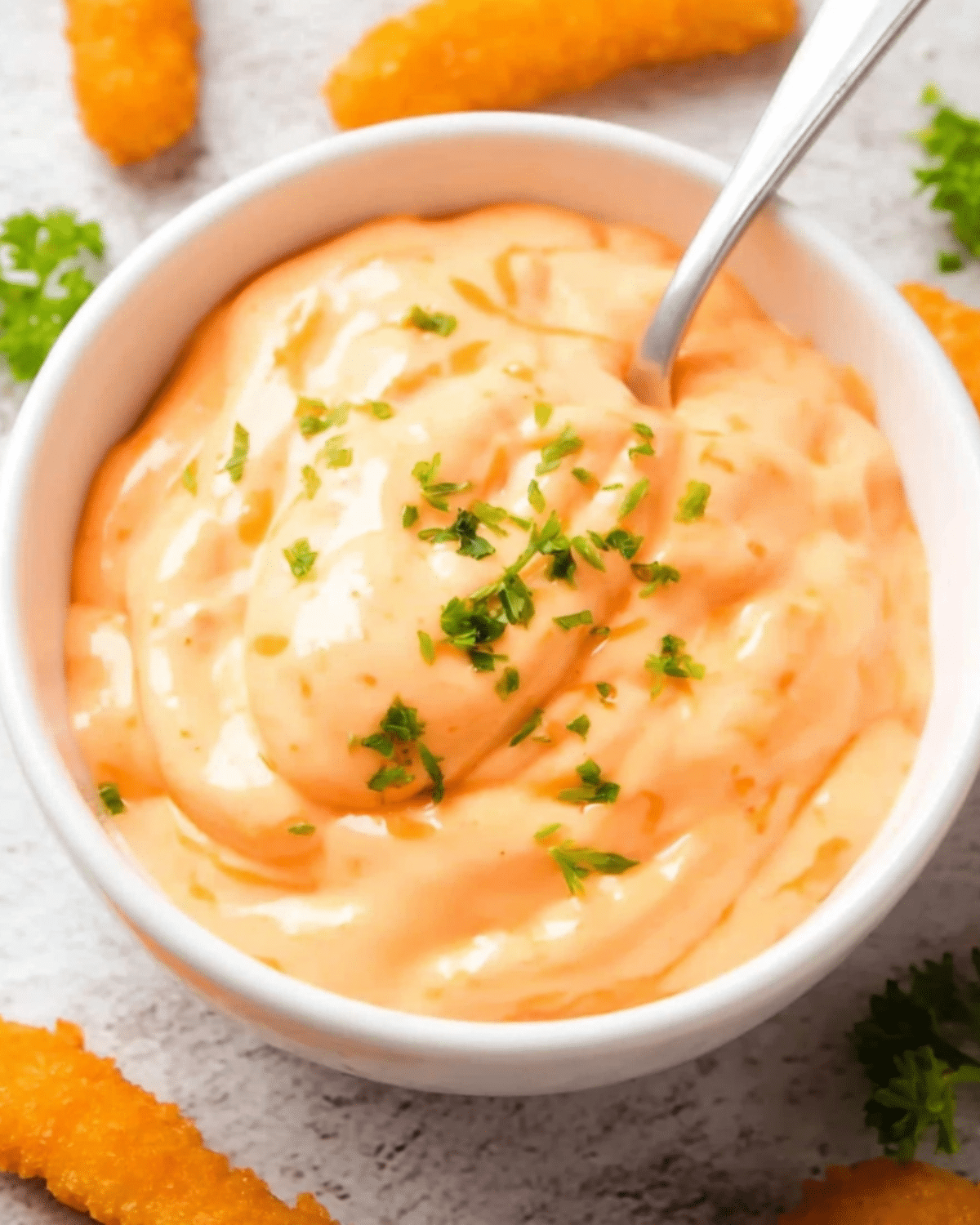 Creamy Big Mac sauce in a white bowl topped with chopped parsley and served with crispy sides.