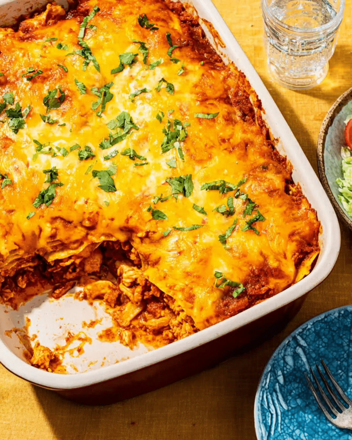 A freshly baked chicken taco casserole in a white baking dish, topped with melted cheese and garnished with chopped cilantro.