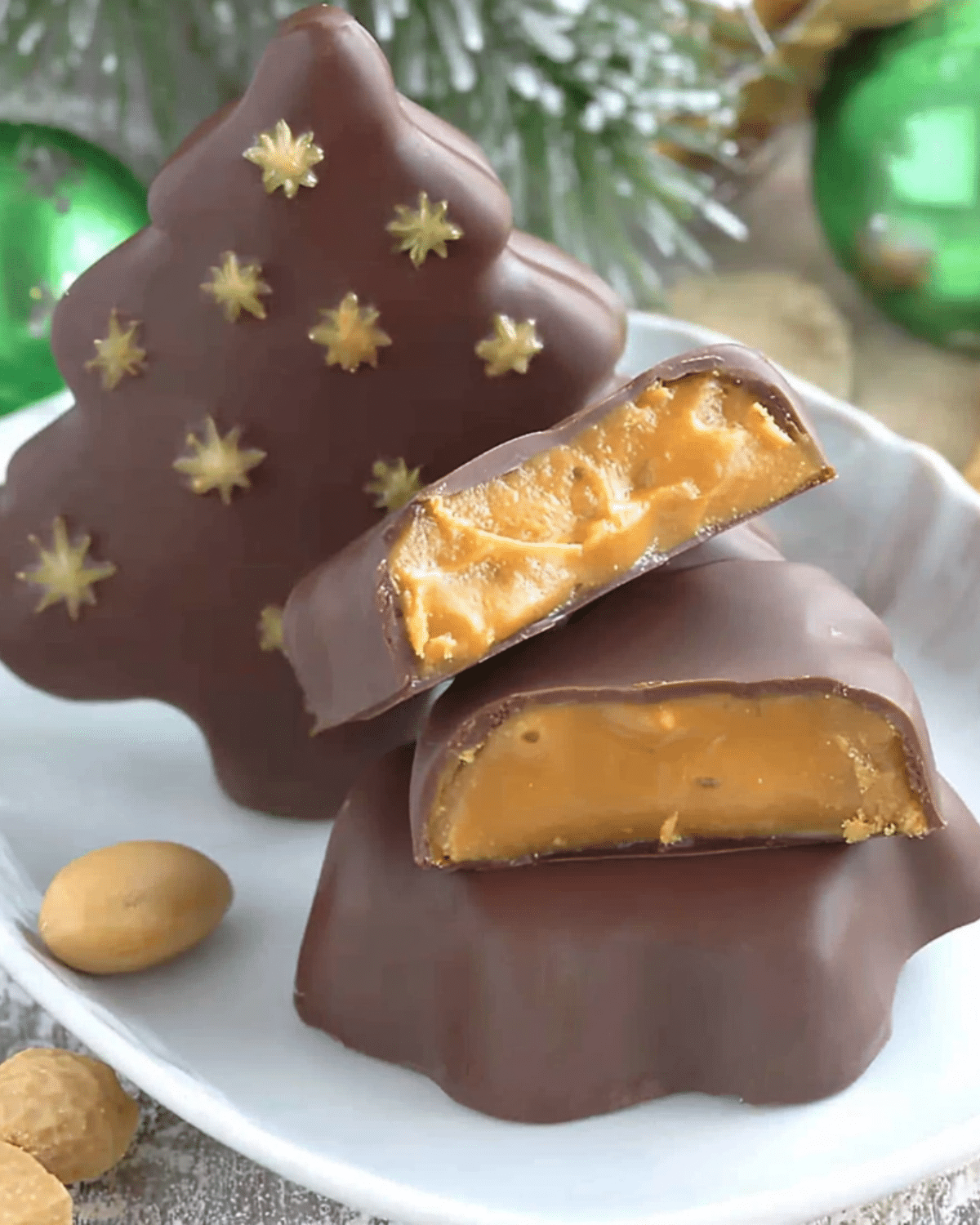 Chocolate peanut butter Christmas trees with a creamy peanut butter filling, coated in chocolate and decorated with golden star accents.