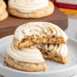Close-up of soft Fireball Cookies topped with swirled cinnamon frosting, with one cookie broken in half to show the moist interior.