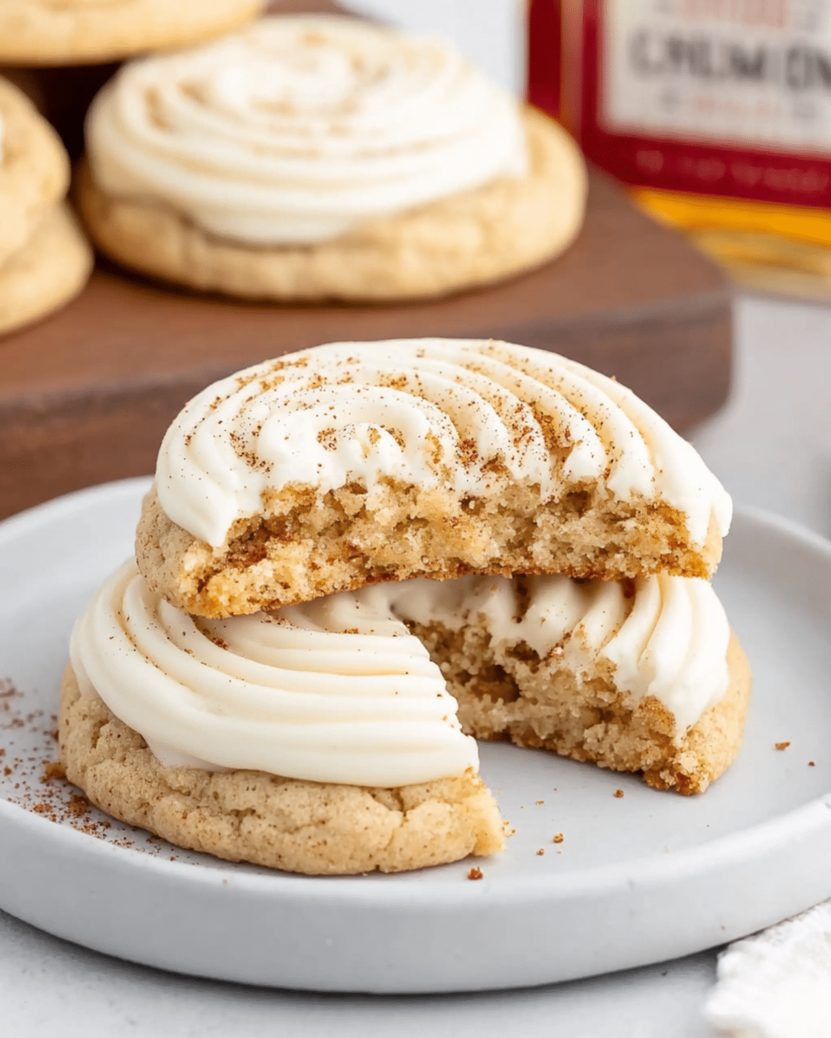Close-up of soft Fireball Cookies topped with swirled cinnamon frosting, with one cookie broken in half to show the moist interior.