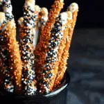 Jar filled with Halloween Pretzel Rods dipped in white chocolate and covered with orange, black, and white sprinkles.