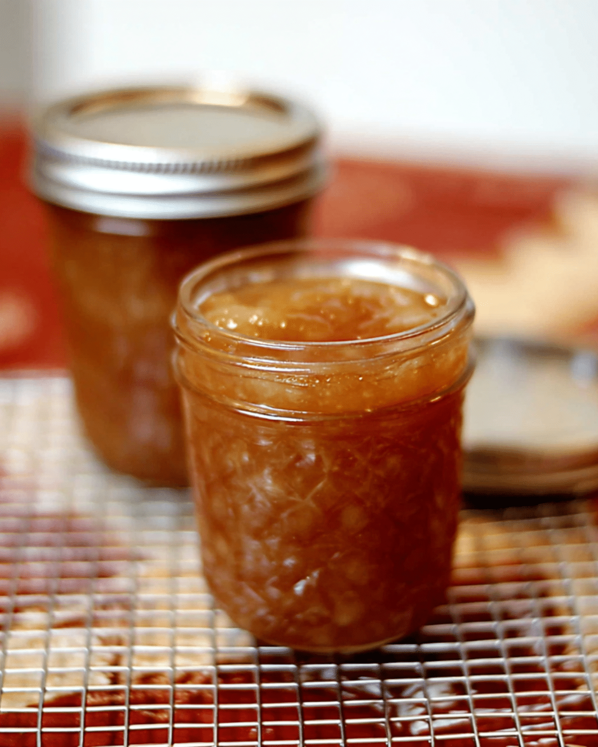 Glass jars filled with Homemade Spiced Honey Pear Jam cooling on a wire rack.
