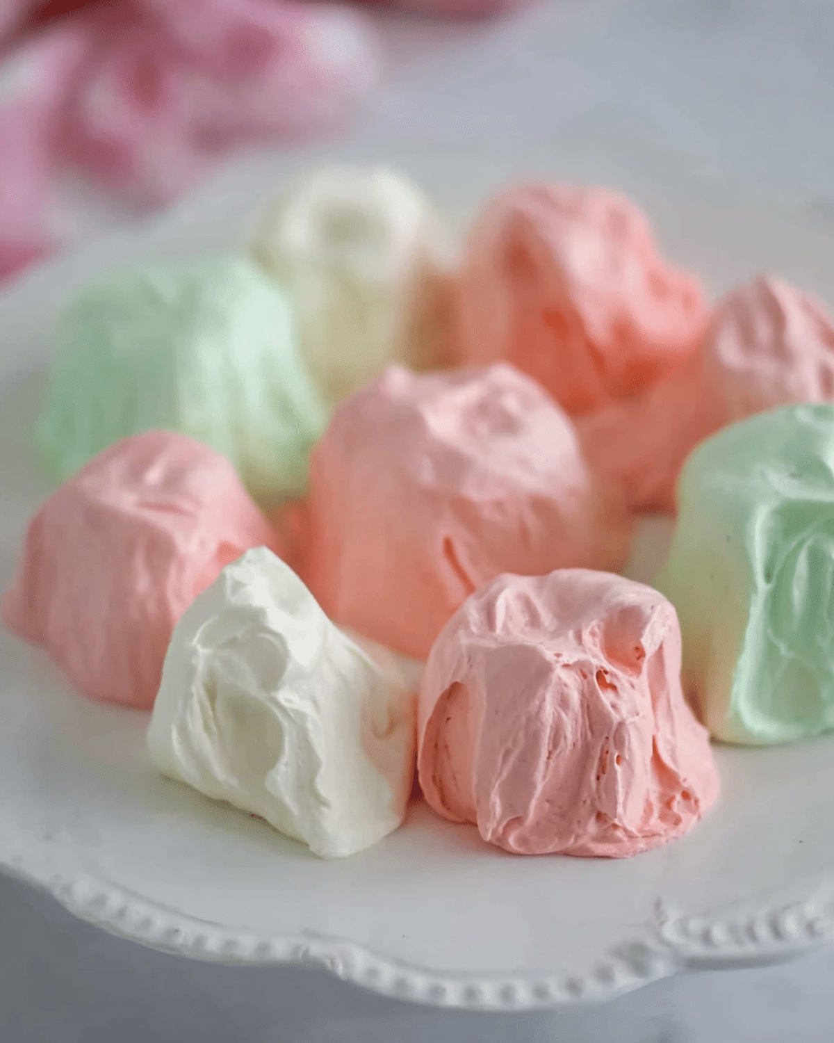 Colorful pieces of Jello Divinity Candy in pastel pink, green, and white arranged on a white plate.