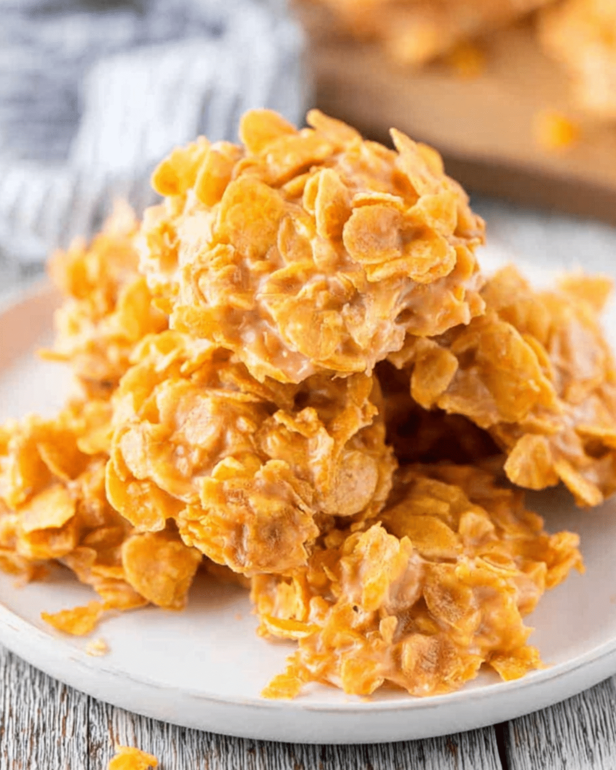 Plate stacked with crunchy No Bake Peanut Butter Cornflake Cookies made with cornflakes coated in a sweet peanut butter mixture.