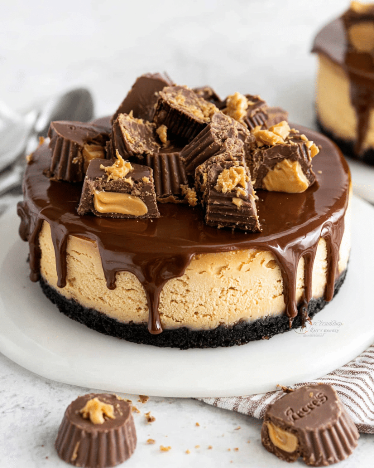 Reese's Peanut Butter Cup Cheesecake topped with chocolate ganache and chunks of peanut butter cups on an Oreo crust.