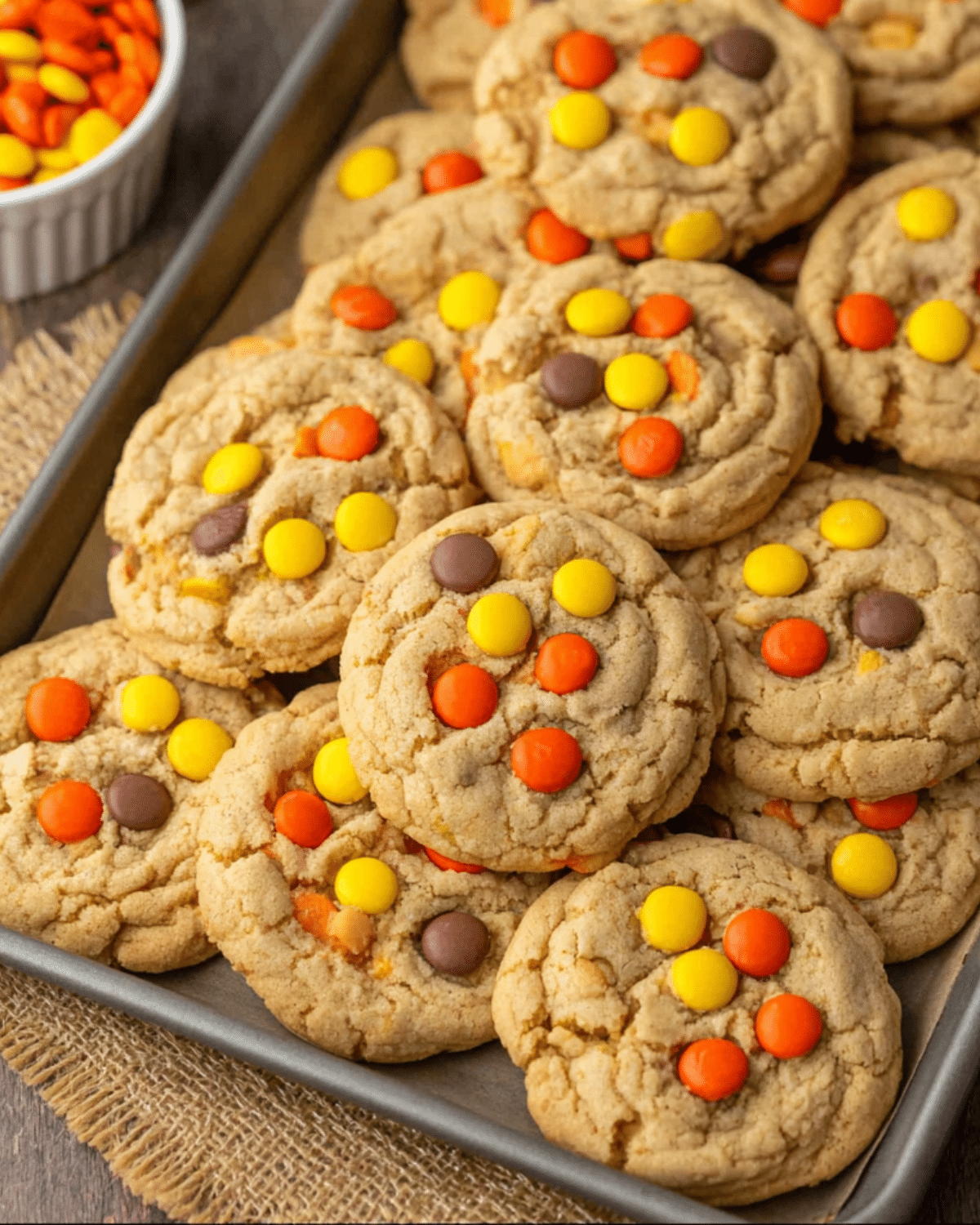 A tray full of freshly baked Reese's Pieces Cookies topped with colorful candy-coated peanut butter pieces.