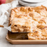 Slice of Sheet Pan Apple Pie being lifted from a golden, flaky pastry filled with spiced apple filling.