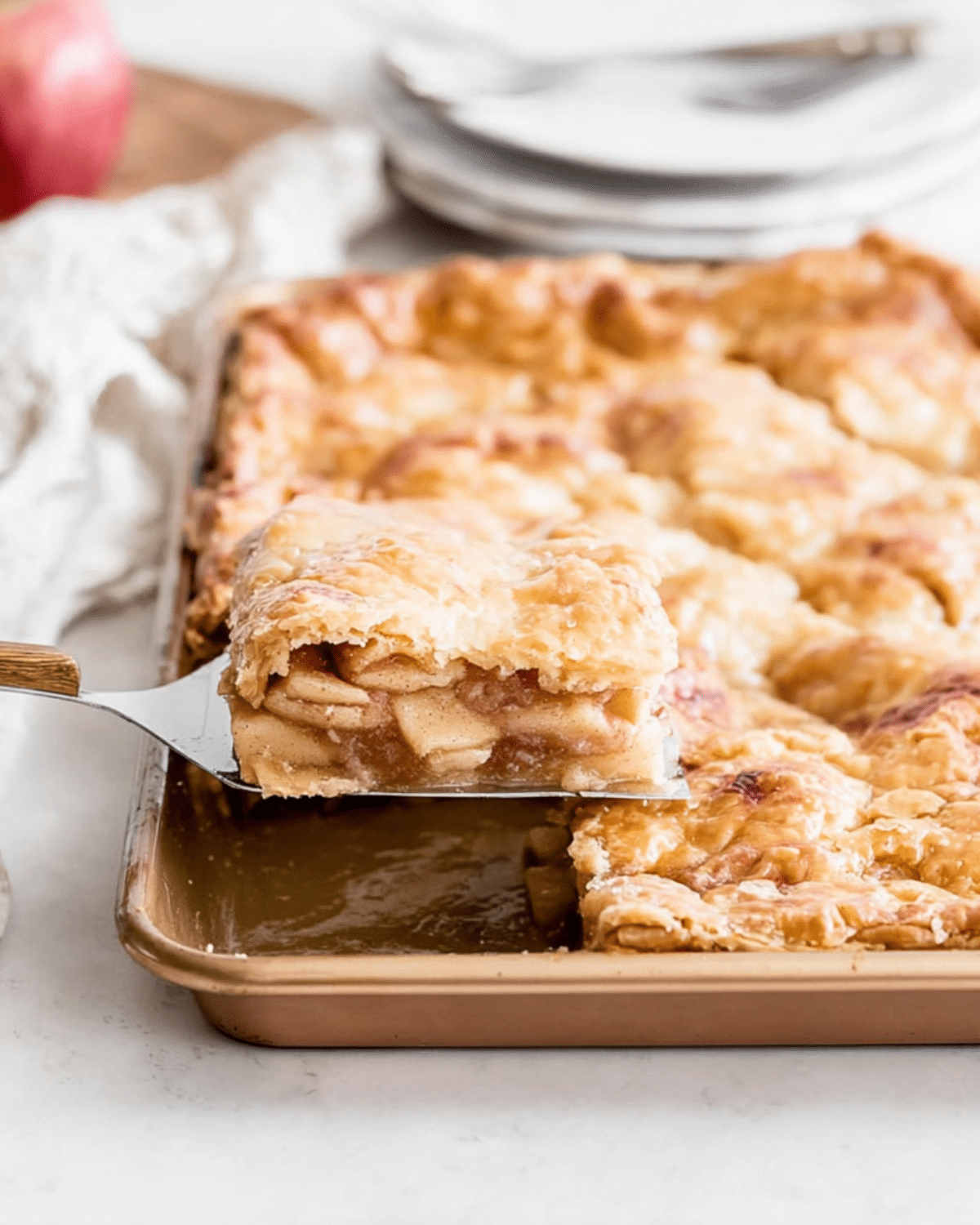 Slice of Sheet Pan Apple Pie being lifted from a golden, flaky pastry filled with spiced apple filling.