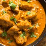 Slow Cooker Coconut Curry Chicken served in a black bowl with tender chicken pieces coated in a creamy coconut curry sauce, garnished with fresh cilantro.