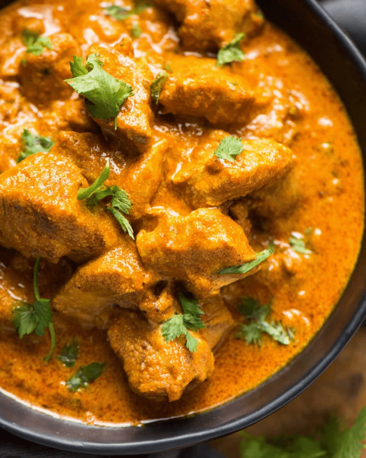 Slow Cooker Coconut Curry Chicken served in a black bowl with tender chicken pieces coated in a creamy coconut curry sauce, garnished with fresh cilantro.