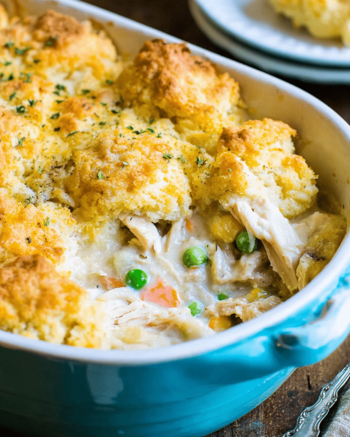 Chicken cobbler in a blue baking dish, topped with golden biscuit crust and filled with creamy chicken and vegetables.
