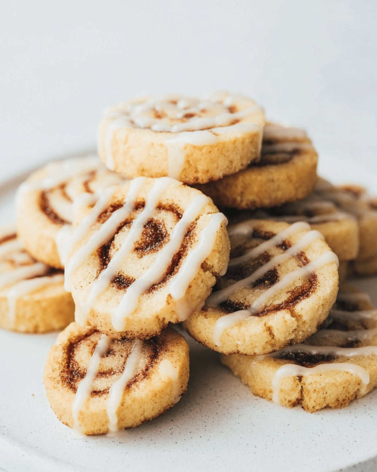 Stack of Cinnamon Roll Cookies drizzled with white icing, showcasing their swirled cinnamon-sugar centers.