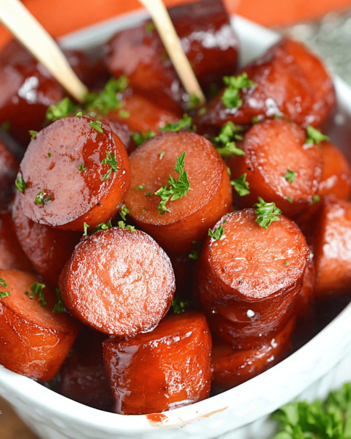 Crockpot Kielbasa Bites garnished with chopped parsley served in a white bowl.