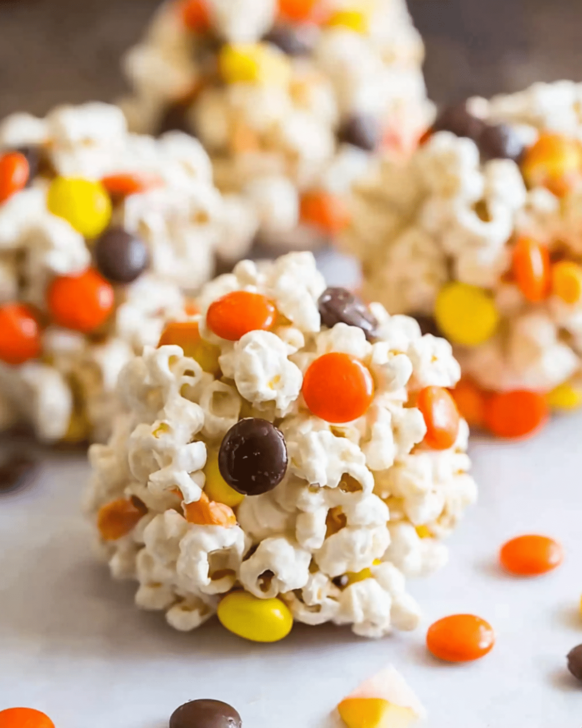 Close-up of Halloween Popcorn Balls packed with popcorn and colorful candy-coated chocolates in festive fall colors.