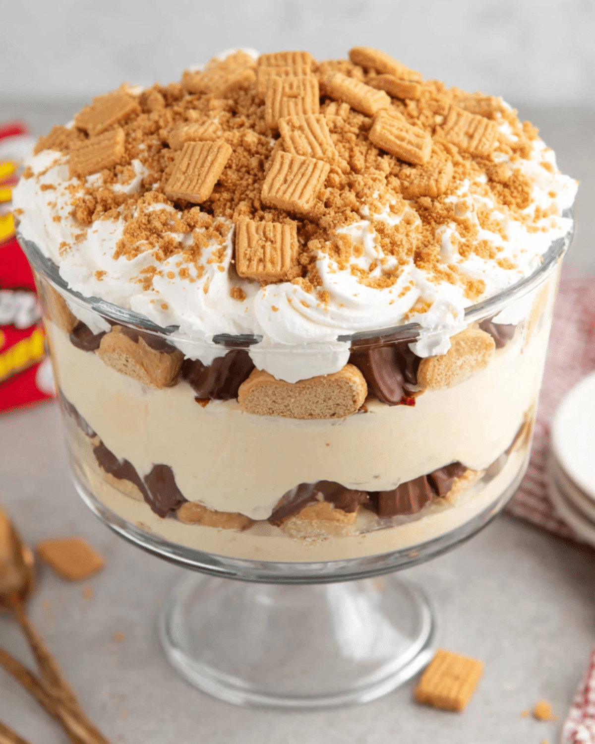 Layered Nutter Butter trifle in a glass dish, filled with whipped cream, pudding, chocolate, and chunks of Nutter Butter cookies.