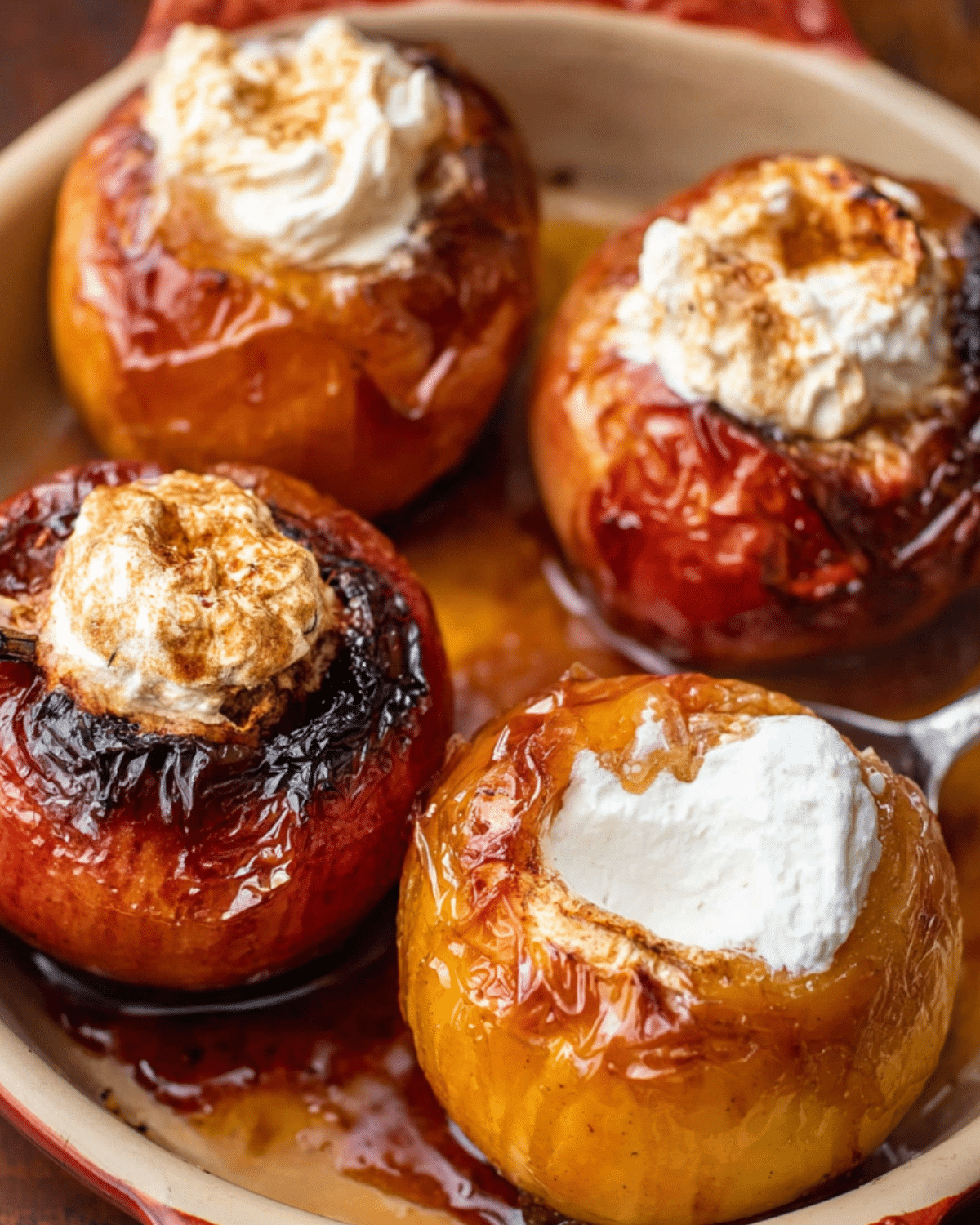 Old-fashioned baked apple dessert with whole caramelized apples filled with whipped cream and cinnamon, served in a baking dish.