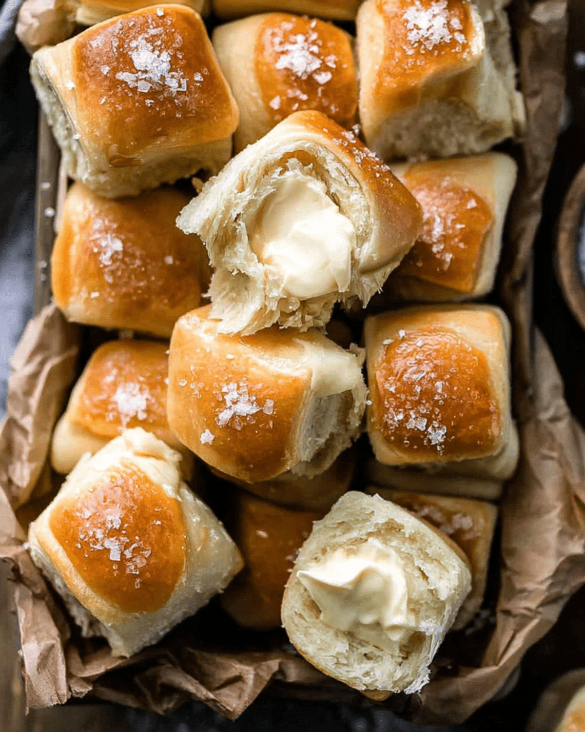 Salted honey butter Parker House rolls stacked in a basket, with golden tops, flaky texture, and creamy butter melting inside.