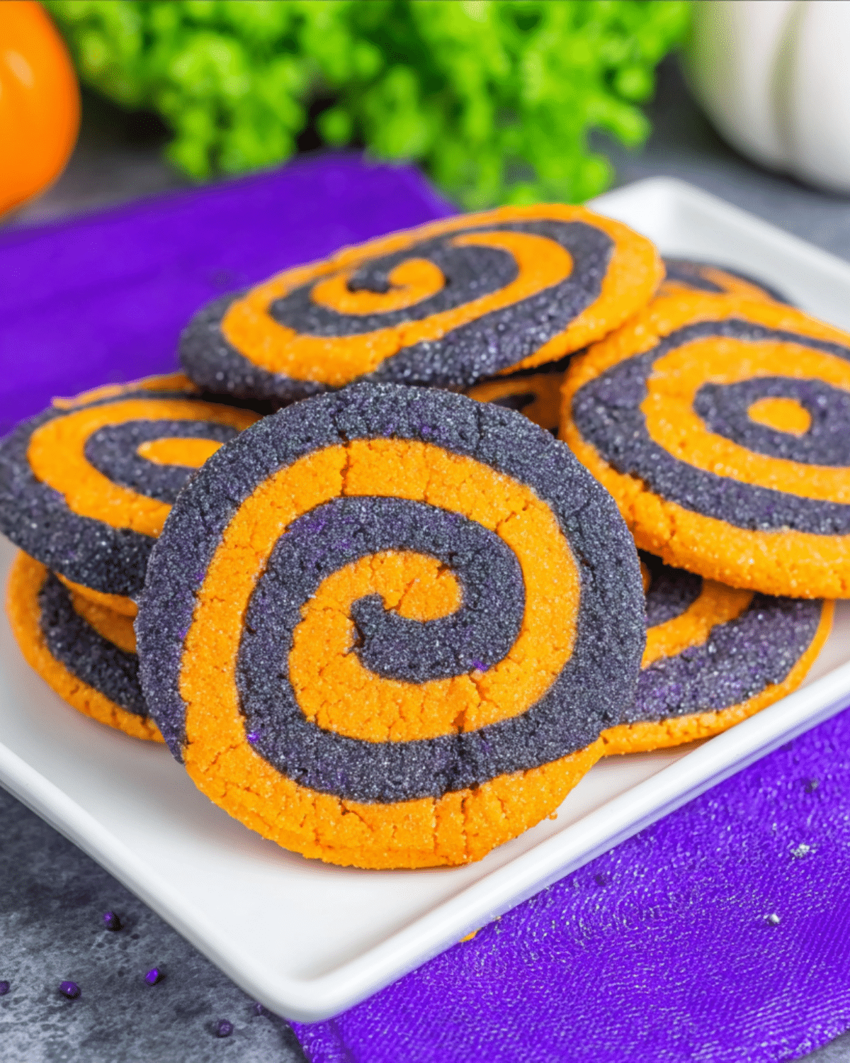 Brightly colored Spiral Halloween Cookies in orange and black sugar swirls on a white plate.