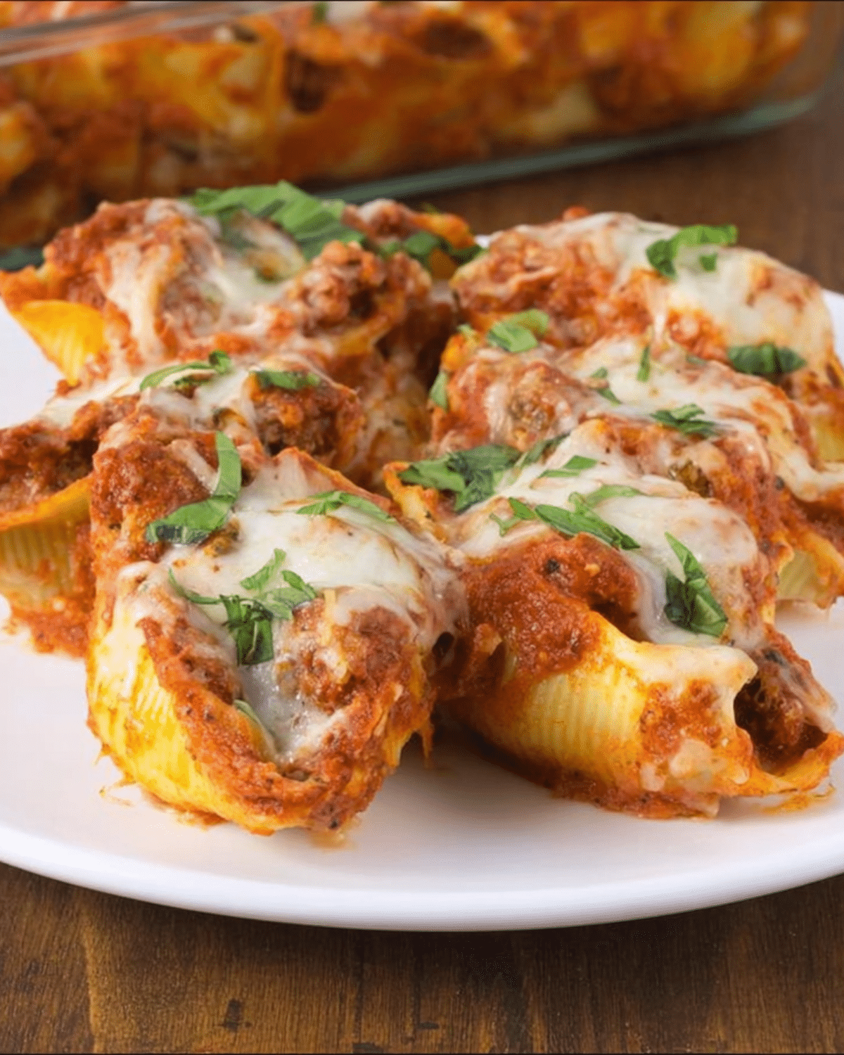 Cheesy Stuffed Shells topped with marinara sauce and fresh basil on a white plate.