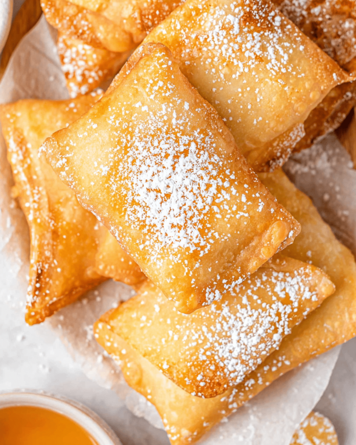 Golden, flaky irresistible Sopapilla pastries dusted with powdered sugar and served with honey.