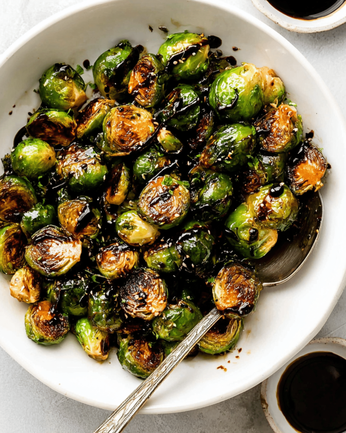 Bowl of Balsamic Glazed Brussels Sprouts with a caramelized finish and serving spoon.
