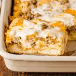 Biscuits and gravy breakfast casserole with sausage, melted cheese, and creamy gravy baked in a casserole dish.