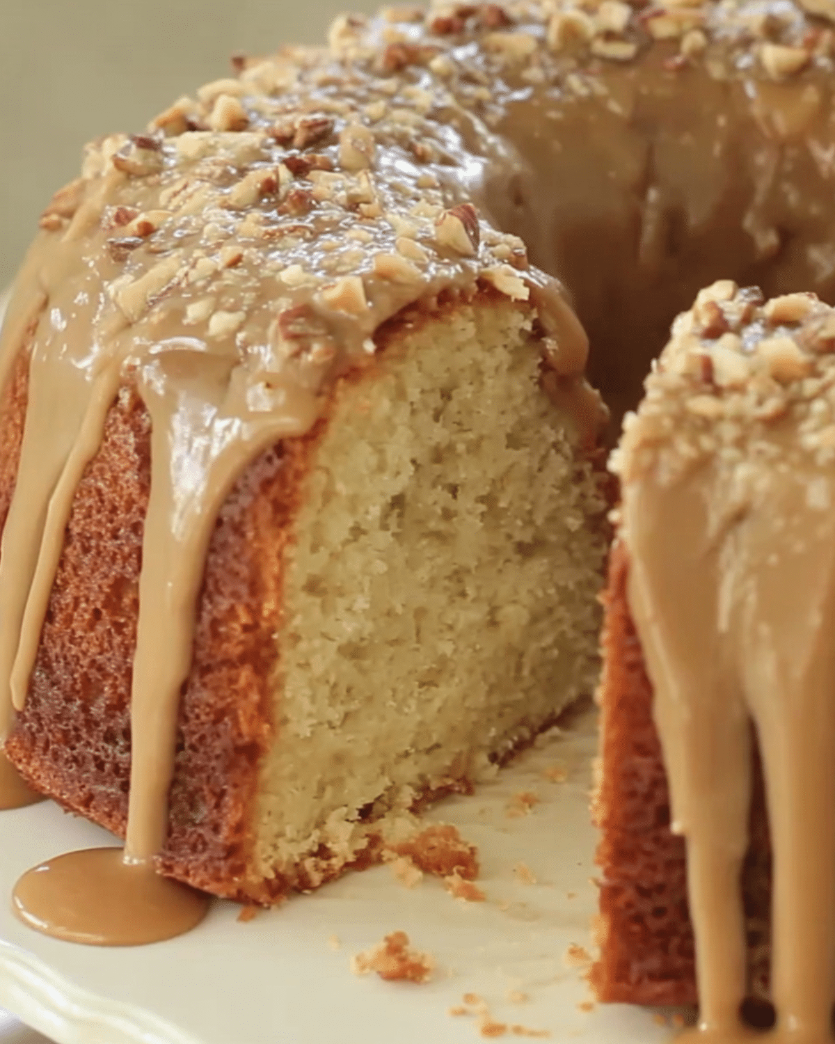 A slice of brown sugar caramel pound cake with thick caramel glaze and chopped pecans on top.
