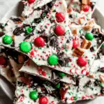 Colorful Christmas candy bark topped with red and green candies, crushed peppermint, sprinkles, and chocolate chunks.