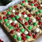 Christmas cookie bars topped with red, green, white candy-coated chocolates and chocolate chips, cut into festive squares.