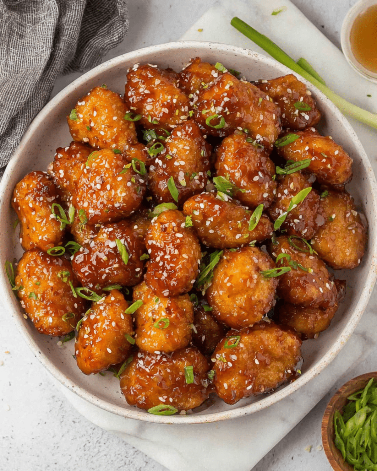 Bowl of Crispy Honey Chicken Bites topped with sesame seeds and chopped green onions.
