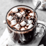 Glass mug filled with Dark Chocolate Hot Chocolate topped with mini marshmallows and chocolate shavings.