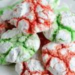 Red and green Festive Crinkle Cookies covered in powdered sugar on a white plate.
