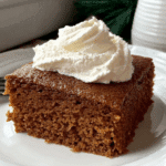 Slice of Gingerbread Crazy Cake topped with whipped cream on a white plate