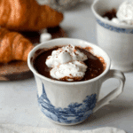 Paris Hot Chocolate served in a white mug with blue Eiffel Tower design, topped with whipped cream and marshmallows.