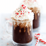 Glass mug of peppermint hot chocolate topped with whipped cream and crushed candy canes.