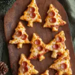 Puff Pastry Christmas Tree Pizza Bites topped with melted cheese and mini pepperoni on a wooden serving board.
