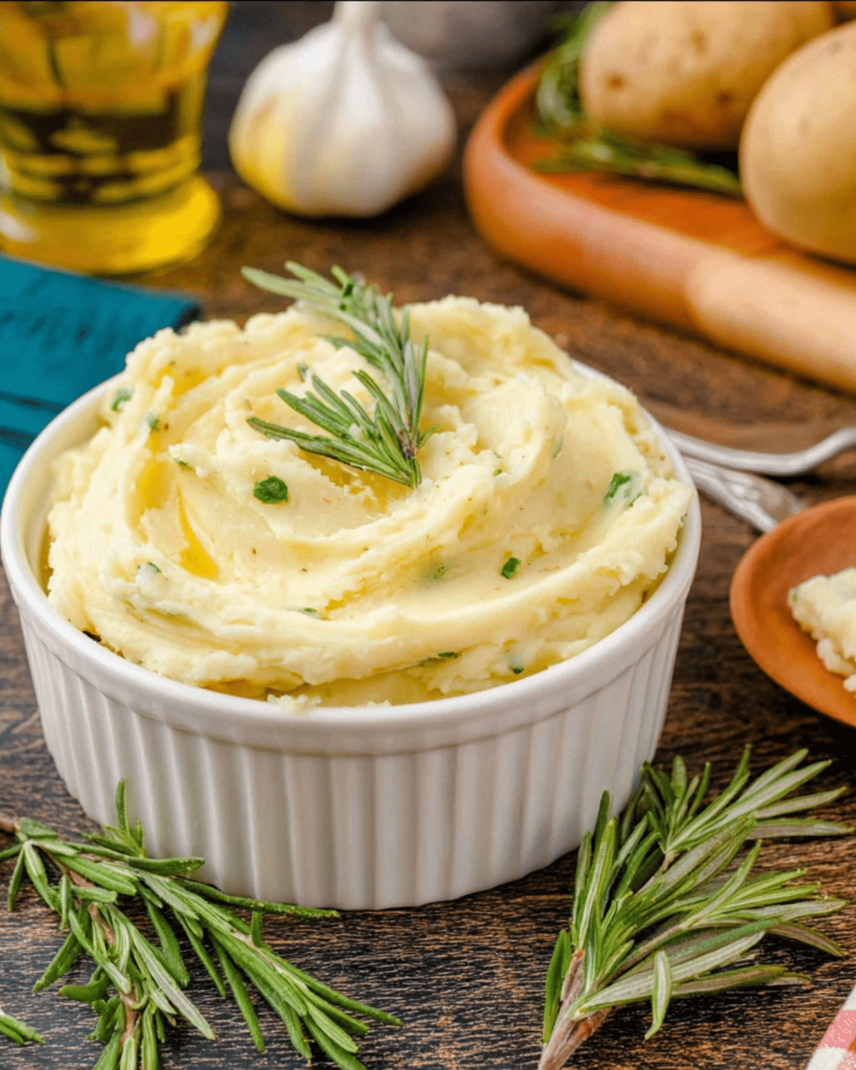 Bowl of rosemary garlic mashed potatoes garnished with fresh rosemary sprigs and herbs.