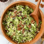Bowl of shredded Brussels sprouts salad with pecans, dried cranberries, and a light dressing.