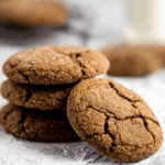 Stack of Super Ginger Molasses Cookies with a sugar-coated crackled surface, resting on parchment paper.