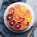 Upside-down ombré citrus cake topped with vibrant slices of blood oranges, navels, and lemons arranged in a gradient.
